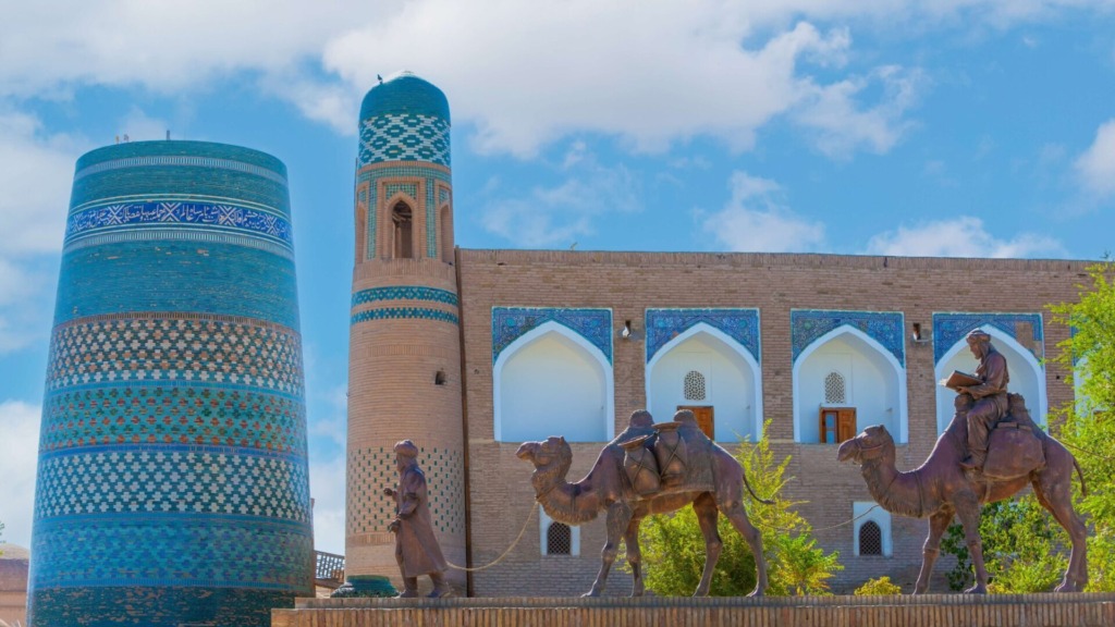 Вид на минарет Кальта-Минар и бронзовые скульптуры паломников, Ичан-Кала.